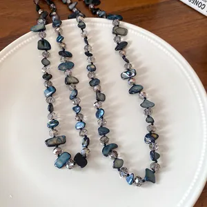 Détail de morceaux de coquillage bleu irréguliers et de perles en verre sur un collier