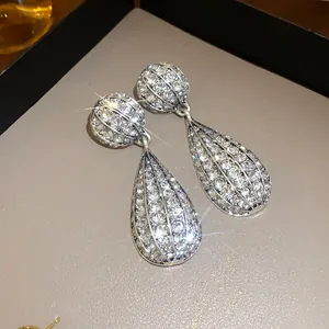 Dettaglio di orecchini a goccia in tonalità argento con cristalli scintillanti.