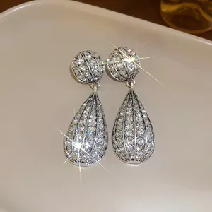 Dettaglio di orecchini a goccia in strass argentati brillanti con riflessi di luce