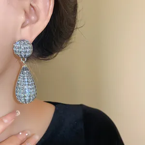 Primo piano di grandi orecchini pendenti argentati di lusso con strass su modella