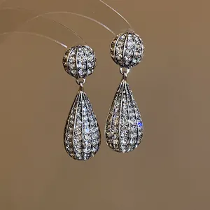 Vista macro dettagliata di orecchini a goccia con pavé di cristalli e finitura argento