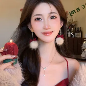Festive Christmas plush pom-pom earrings with red bow on elegant Asian model