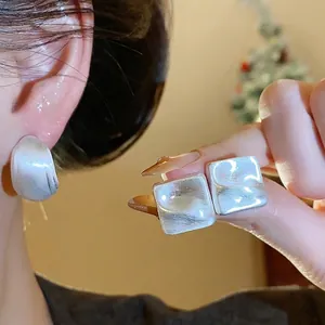 Orecchini a perno quadrati minimalisti in argento con texture spazzolata, scatto lifestyle
