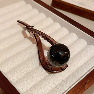 Detail of a dark brown resin duckbill hair clip with a large black round bead ornament