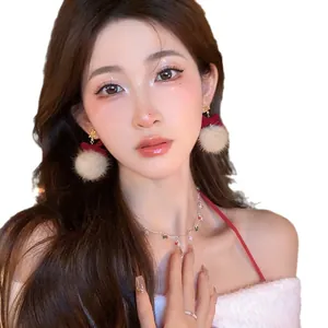 Festive Christmas earrings with soft plush pom poms and red bows on an Asian model