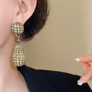 Dettaglio di orecchini a goccia dorati con strass scintillanti per uno stile glamour
