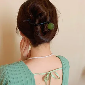 Detailed view of a Korean minimalist hair clip with a green resin ball in a hair bun