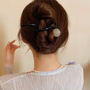 Close-up of minimalist resin ball hair clip worn on a brown bun hairstyle for women