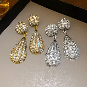 Primo piano dettagliato di orecchini a goccia in oro e argento con strass incastonati.