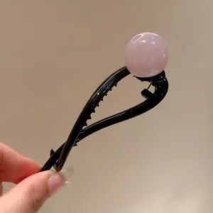 Detailed view of a minimalist pink resin ball hair clip on a black duckbill base