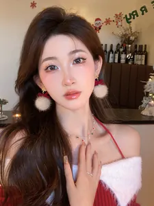 Close-up of model wearing plush Christmas ball earrings with red bows and necklace