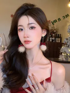 Asian model wearing Christmas plush ball bow earrings with snowflake studs in festive setting