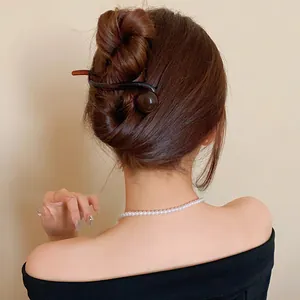 Close-up of a minimalist dark brown resin hair clip elegantly worn in a stylish hair bun