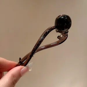 Detailed view of an elegant dark brown resin hair clip with a stylish black bead