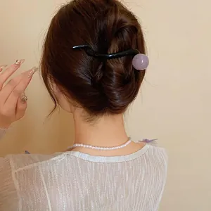 Elegant Korean style purple resin ball hair clip shown as a detail on a low bun hairstyle