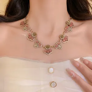 Detailed view of a French retro floral necklace with pink cat's eye stones and sparkling crystals