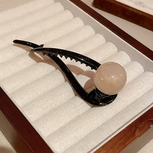 Close-up of minimalist black resin duckbill clip with a smooth pink pearl-like resin ball.