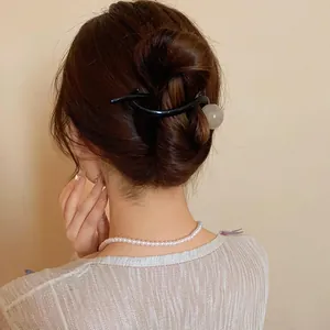 Detailed view of a minimalist black resin hair clip with bead on an elegant bun hairstyle