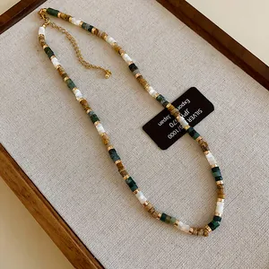 Close-up of ethnic style beaded necklace with shell and green stone beads on a tray