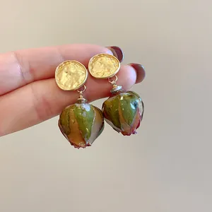 Dettaglio di orecchini vintage in oro martellato con veri boccioli di rosa conservati a mano
