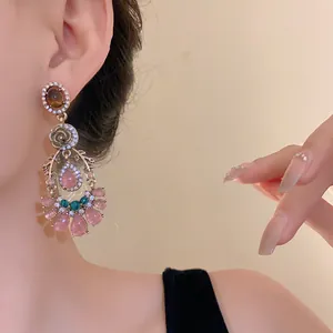 Vintage court style drop earrings with pink stones and floral rhinestone details on ear.