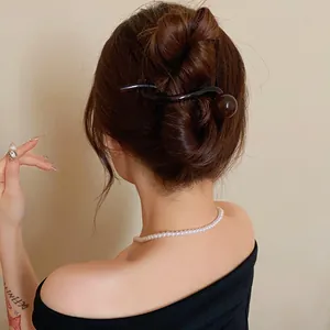 Macro view of a minimalist brown resin hair clip with a round ball end styled in a bun