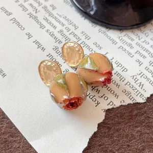 Dettaglio degli orecchini con rose stabilizzate e perni in metallo martellato color oro.