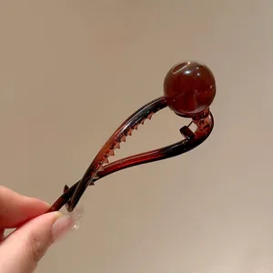 Macro view of minimalist amber resin hair clip featuring a glossy decorative round ball