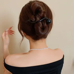 Detailed view of a minimalist black resin hair clip styled in a modern bun hairstyle
