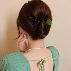 Back view of a woman wearing a minimalist black hair clip with a green resin bead