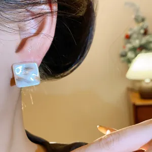 Primo piano di una modella che indossa un orecchino a perno quadrato argento minimalista