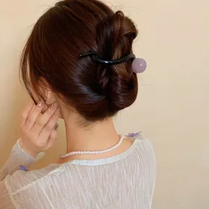 Elegant resin duckbill hair clip with purple bead detail shown on model's styled hair.