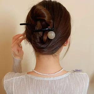 Elegant black hair clip featuring a round resin ball shown in a stylish bun hairstyle