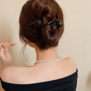Detail showing a black minimalist resin hair clip with sphere end in a hair bun
