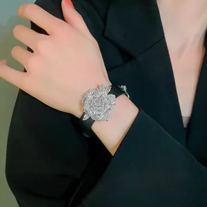 Sparkling rhinestone flower bracelet with black leather strap shown on a model's wrist