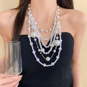 Detailed view of multi-layer statement pearl necklace worn by model in black dress