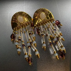 Detailed view of vintage ethnic gold earrings featuring beaded tassels and purple crystals