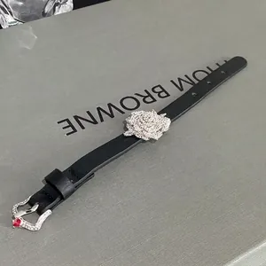 Elegant black leather belt bracelet with a sparkling rhinestone flower charm and heart buckle