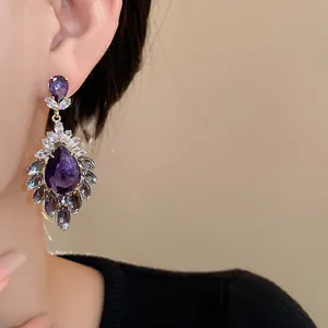 Dettaglio di orecchini vintage con gocce viola e zirconi scintillanti di lato.