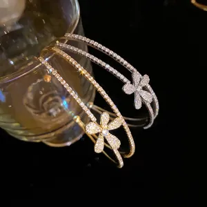Elegant double-layer open bangle with sparkling cubic zirconia flower charms.