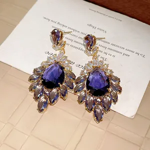 Primo piano di orecchini vintage in zircone viola a forma di goccia con petali floreali.
