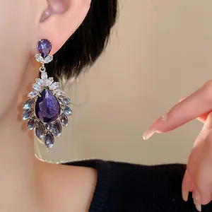 Dettaglio di orecchini vintage a goccia viola con zirconi scintillanti su modella.