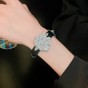 Detailed macro view of a sparkling crystal rose flower charm on an elegant black leather strap bracelet