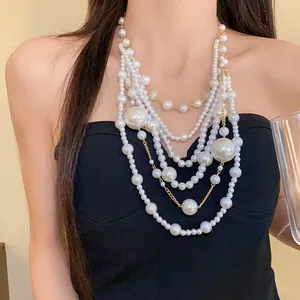 Elegant multi-layer pearl necklace with varied bead sizes and gold-tone chains on model
