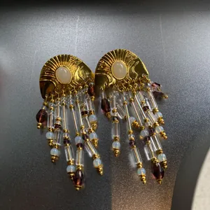Detailed macro view of vintage gold sunburst earrings with elegant beaded long tassels