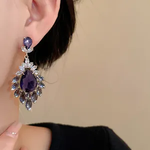 Vista dettagliata di orecchini vintage in zircone a goccia viola con design floreale su modella