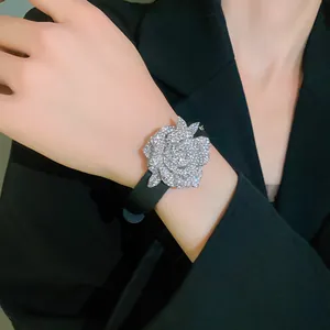 Detail view of a sparkling rhinestone flower bracelet on a black leather strap