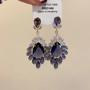 Dettaglio di orecchini vintage a goccia con zirconi blu e trasparenti