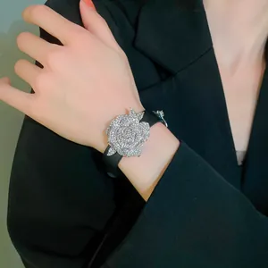 Detailed view of a sparkling rhinestone rose flower bracelet on black leather strap.