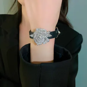 Close-up of a sparkling rhinestone rose flower charm on a black leather strap bracelet